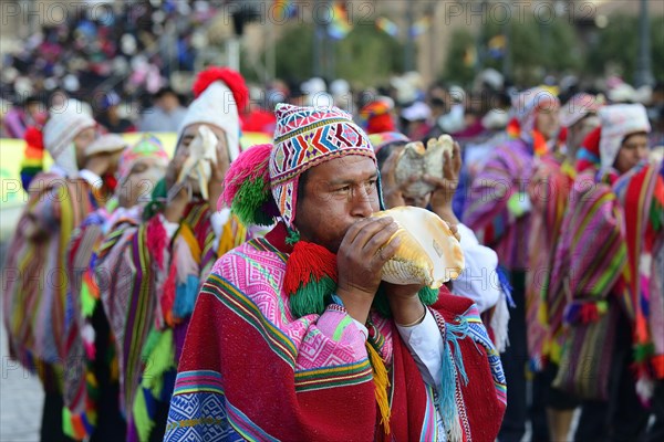 Indigenous man blows conch shell during parade on eve of Inti Raymi