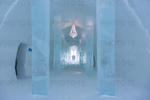 Long corridor with table and chandelier made of ice in the ice hotel of Jukkasjaervi