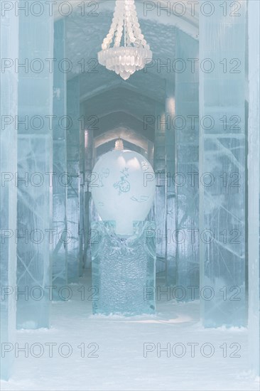 Long corridor with table and chandelier made of ice in the ice hotel of Jukkasjaervi