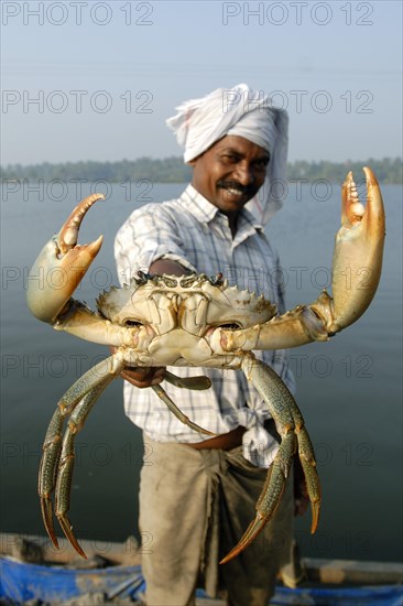 Ein Mann haelt eine riesige Krabbe