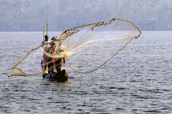 Ein Fischer Mann wirft das Fischernetz in Backwaters von Cherai