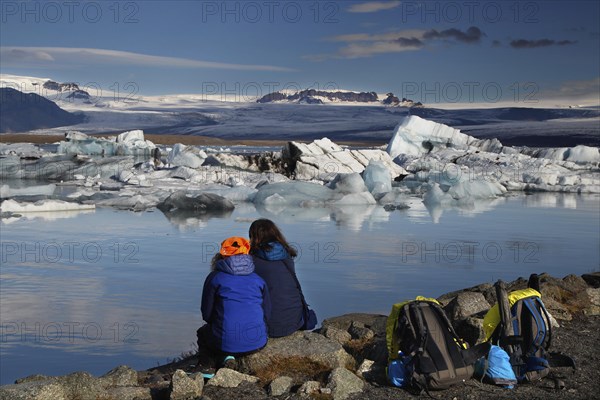 Back view of two tourists with backpacks at the water