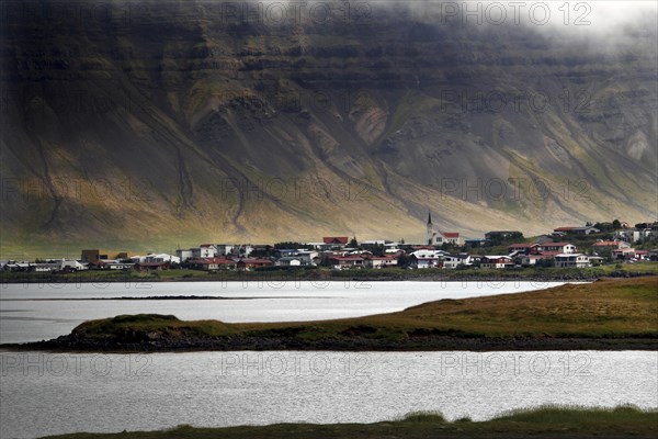 Fishing village on headland in front of mountain scenery