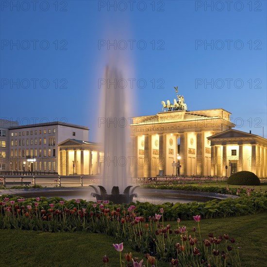 Illuminated Brandenburg Gate with fountain and Pariser Platz in the evening