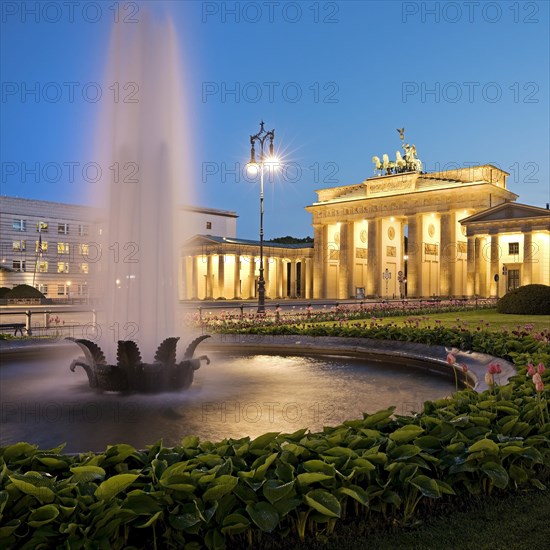 Illuminated Brandenburg Gate with fountain and Pariser Platz in the evening