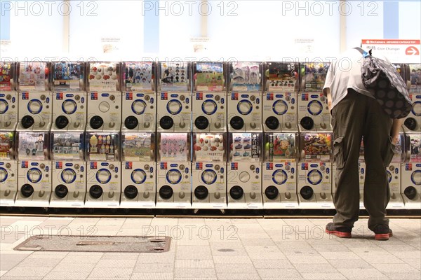 Man using Gashapon capsule toy vending machines in Akihabara