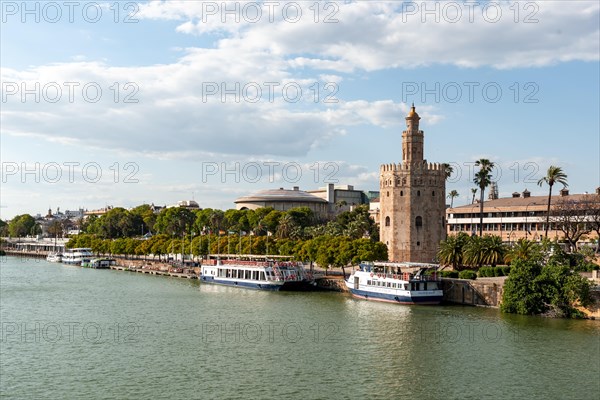 View over the river Rio Guadalquivir on promenade with excursion boats and Torre del Oro