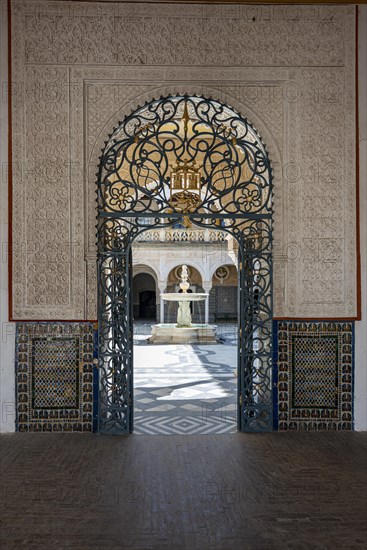 View through a door decorated with arabesques into the inner courtyard with fountain