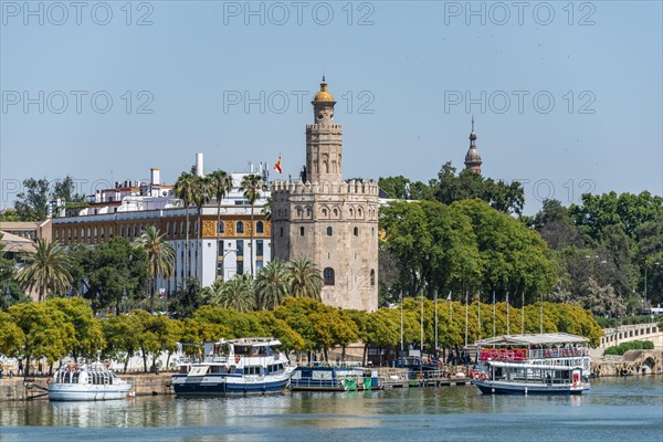 View over the river Rio Guadalquivir on promenade with excursion boats and Torre del Oro