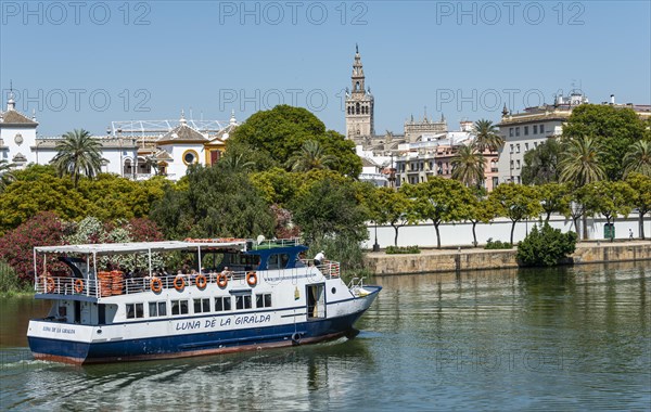 View over the river Rio Guadalquivir to the promenade with excursion boats and La Giralda