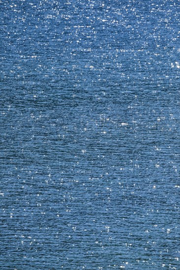 Sunbeams reflect glittering on the water surface of the Vierwaldstaettersee and form an abstract pattern