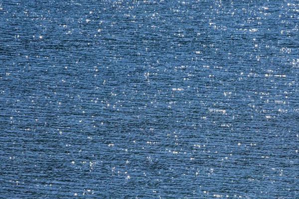 Sunbeams reflect glittering on the water surface of the Vierwaldstaettersee and form an abstract pattern