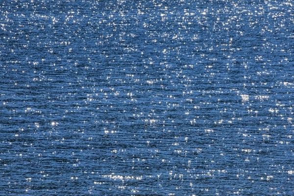 Sunbeams reflect glittering on the water surface of the Vierwaldstaettersee and form an abstract pattern