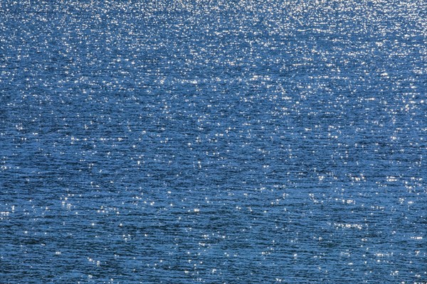 Sunbeams reflect glittering on the water surface of the Vierwaldstaettersee and form an abstract pattern