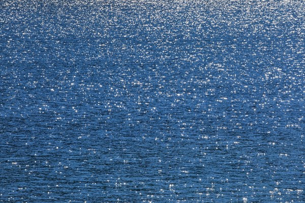 Sunbeams reflect glittering on the water surface of the Vierwaldstaettersee and form an abstract pattern