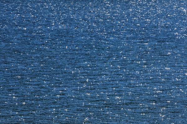 Sunbeams reflect glittering on the water surface of the Vierwaldstaettersee and form an abstract pattern