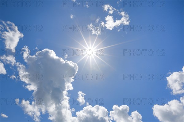 Sun star in blue sky with some source clouds in backlight