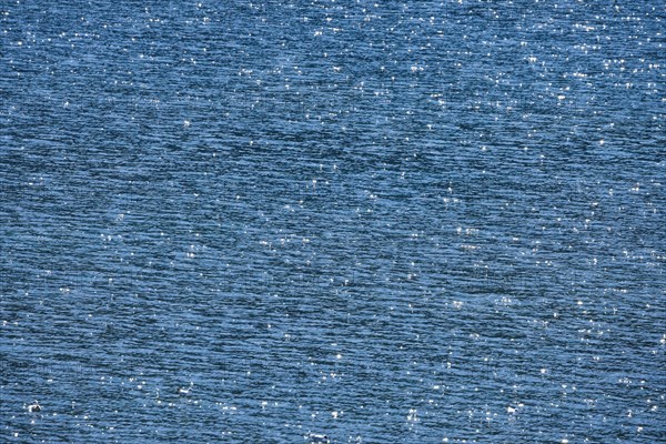 Sunbeams reflect glittering on the water surface of the Vierwaldstaettersee and form an abstract pattern