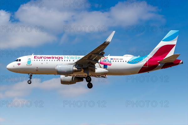 A Eurowings Airbus A320 with the registration OE-IQD and the special livery Holidays lands at London Heathrow Airport