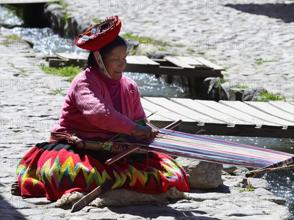 Indigenous woman sitting on paved path weaving