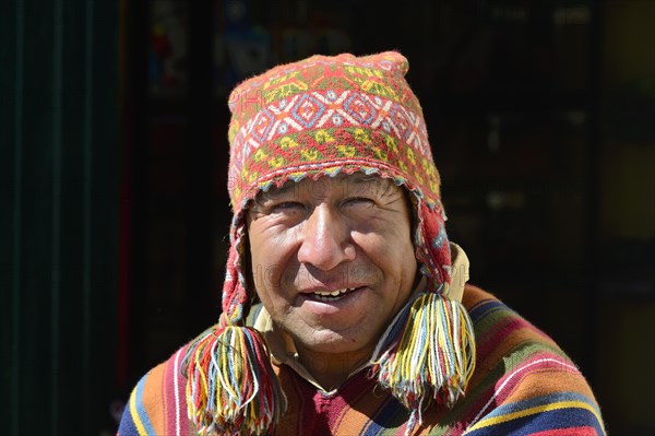 Indigenous man in colorful poncho and cap