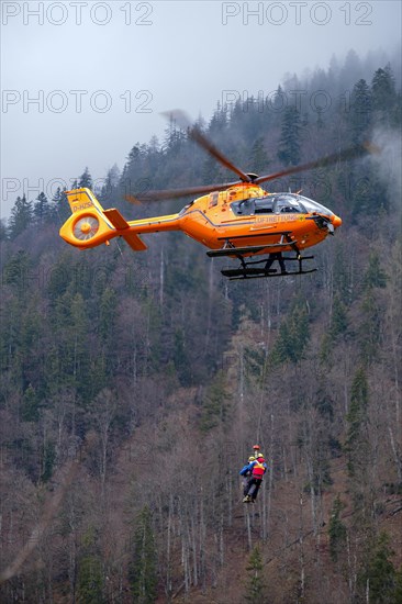Two flight rescuers of the Bavarian Mountain Rescue Service hang on the wire rope of the rescue helicopter Christoph 14