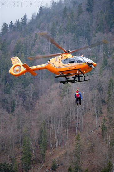 Two flight rescuers of the Bavarian Mountain Rescue Service hang on the wire rope of the rescue helicopter Christoph 14