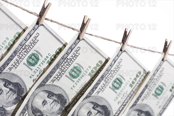 Hundred dollar bills hanging from clothesline on a white background
