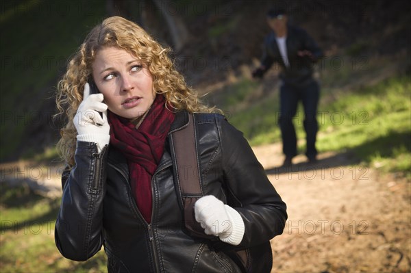 Pretty young teen girl calling on cell phone with mysterious strange man lurking behind her