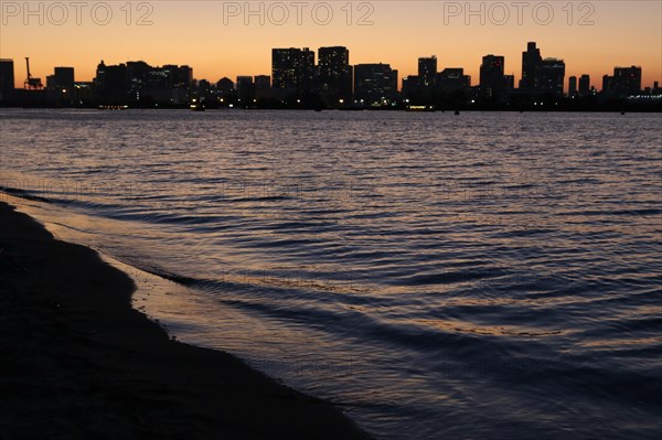 View from Odaiba Beach to Tokyo Bay with skyline silhouette at dusk