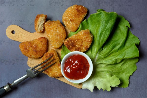 Meat substitute on wooden board and tray with ketchup