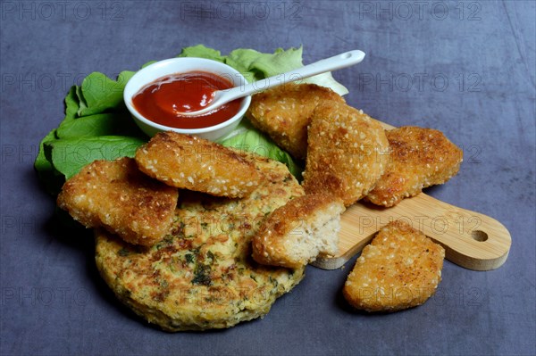 Meat substitute on wooden board and tray with ketchupl