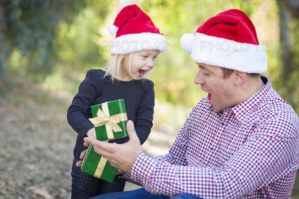 Happy father giving young daughter A christmas gift outdoors