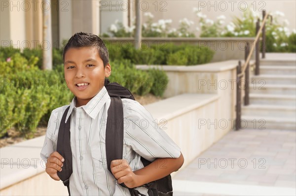 Happy hispanic boy with backpack walking on school campus