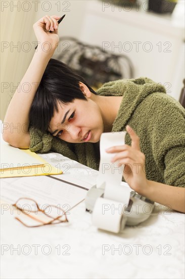 Multi-ethnic young woman agonizing over financial calculations in her kitchen