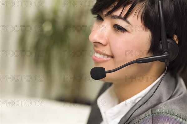 Attractive young mixed-race woman smiles wearing headset in office setting