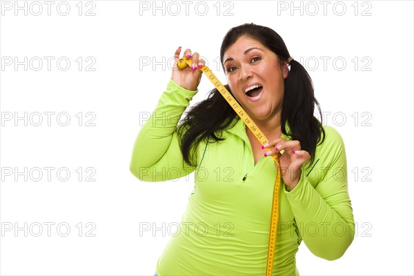 Attractive middle aged hispanic woman in workout clothes showing off her tape measure against a white background