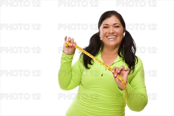 Attractive middle aged hispanic woman in workout clothes showing off her tape measure against a white background