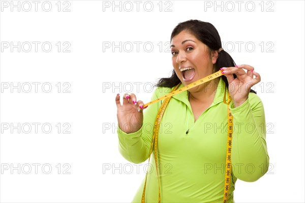 Attractive middle aged hispanic woman in workout clothes showing off her tape measure against a white background