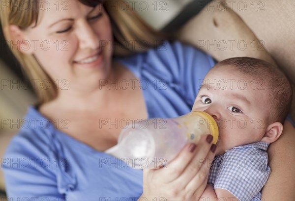 Happy mother bottle feeding her very content son