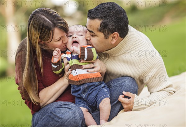 Happy mixed-race parents playing with their giggling son