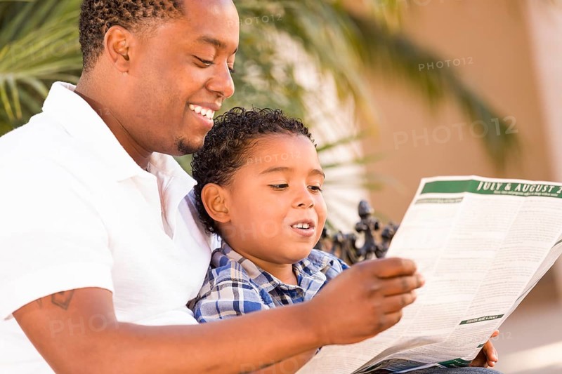 Happy african american father and mixed-race son having fun reading ...