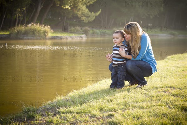 Happy mother and baby son looking out at the pretty lake