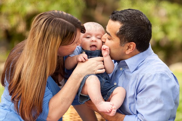 Happy mixed-race parents playing with their giggling son