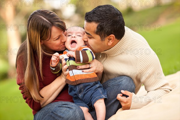 Happy mixed-race parents playing with their giggling son