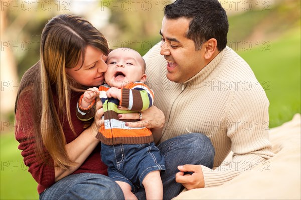 Happy mixed-race parents playing with their giggling son