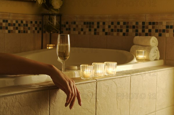 Beautiful woman in bubble bath with sparkling wine and candles surrounding her