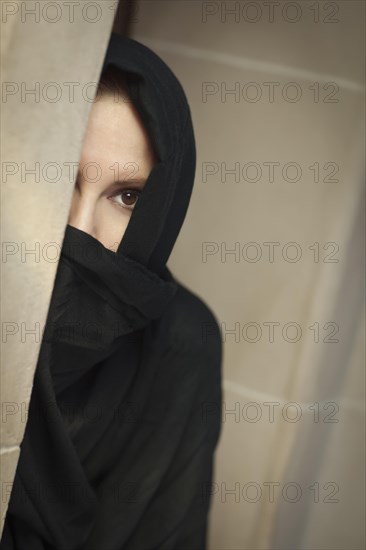 Cautious islamic woman in a window pane wearing traditional burqa or niqab