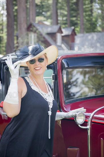 Attractive young woman in twenties outfit near antique automobile