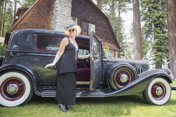 Attractive young woman in twenties outfit near antique automobile